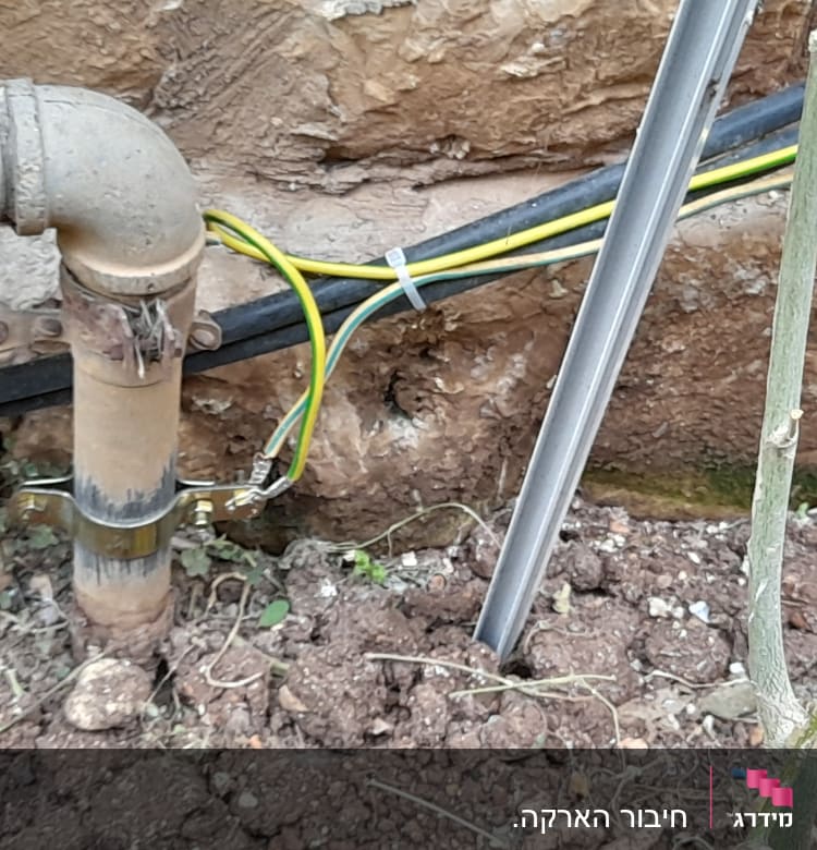 צינור מתכת עם חוטי חשמל צהובים וירוקים